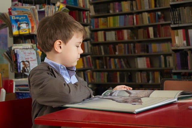 chłopiec-czyta-książkę-w-bibliotece