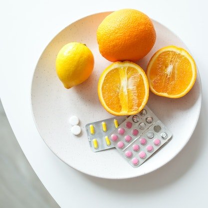 Pomarańcze i suplementy z witaminami na talerzu