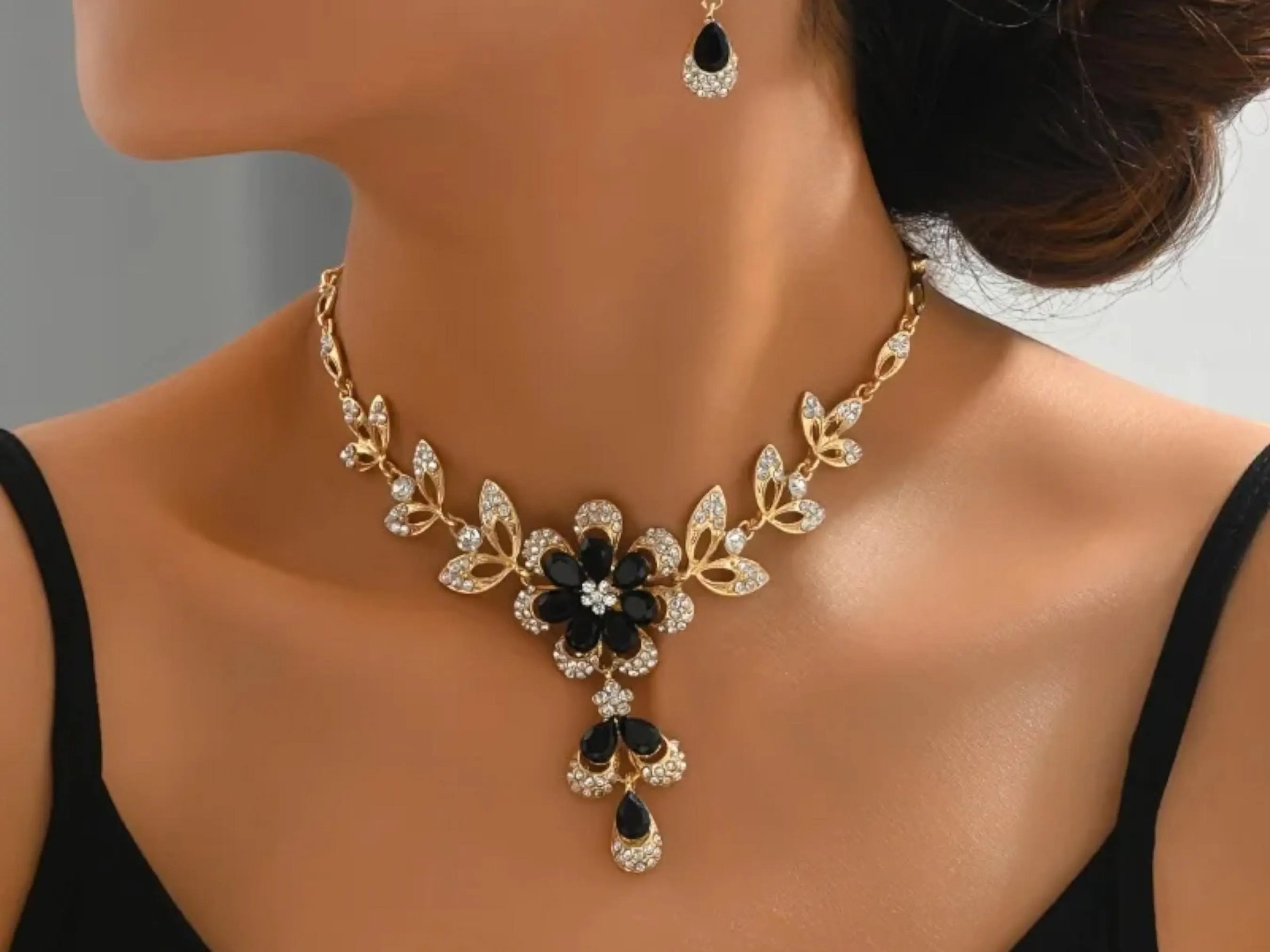 Złota biżuteria i naszyjnik jako dodatki do czarnej sukienki